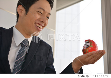 だるまを手のひらに載せて、微笑む若いビジネスマン、リラックス 31463329