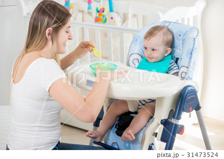 Young mother feeding her baby boy with fruit sauce 31473524
