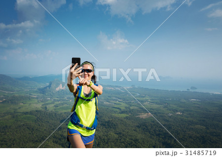 hiker taking photo with cellphone on mountain peak hiker taking photo with cellphone on mountain peak 31485719