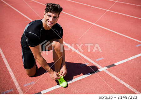 Portrait of male athlete tying her shoe laces on running track 31487223