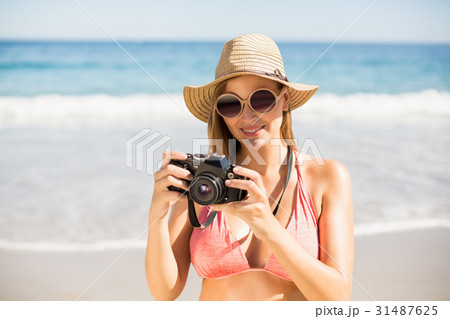 Attractive woman in bikini checking photographs Attractive woman in bikini checking photographs 31487625