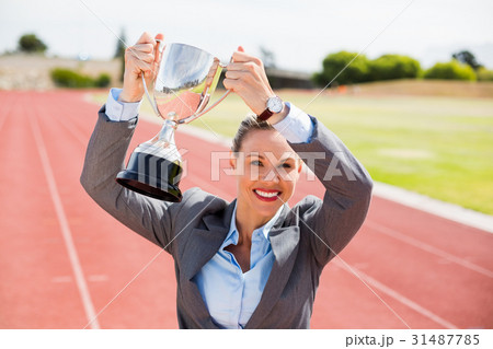Portrait of happy businesswoman holding up a trophy 31487785