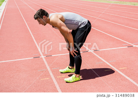 Tired athlete standing on running track 31489038
