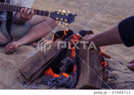 friends sitting on stones on beach. man is playing friends sitting on stones on beach. man is playing 31489711