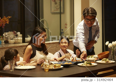 a happy family of parents and two kids has dinner at home together a happy family of parents and two kids has dinner at home together 31492464