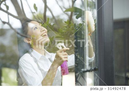 young lady is smiling and cleaning the glass window young lady is smiling and cleaning the glass window 31492478