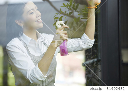 a woman is smiling and cleaning glass window a woman is smiling and cleaning glass window 31492482