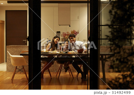 a portrait of parents and daughter sitting at dining table at home 31492499