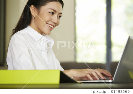 young woman is smiling and working on a laptop young woman is smiling and working on a laptop 31492569