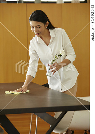 a maid is cleaning the table and holding a flower vase. 31492643