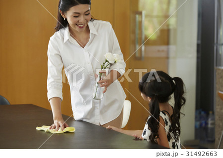 mom is talking to daughter when holding a vase and clean a table. mom is talking to daughter when holding a vase and clean a table. 31492663