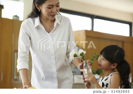 kid is holding vase for her mom to clean something. 31492693