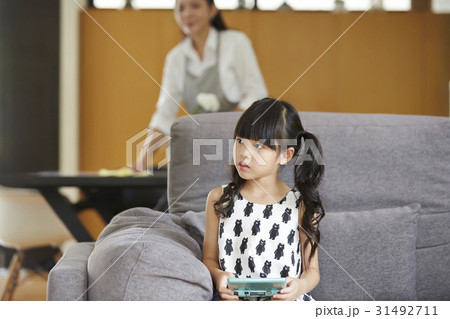 A photo of cute little girl sitting on the sofa at home. A photo of cute little girl sitting on the sofa at home. 31492711
