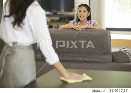 The little girl is smiling and looking her mother cleaning. The little girl is smiling and looking her mother cleaning. 31492717