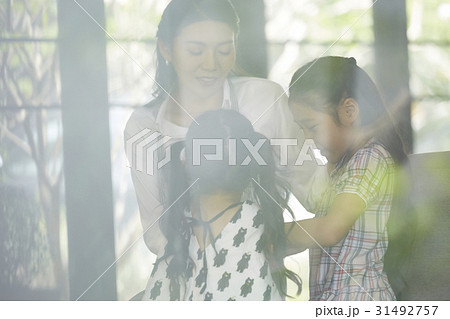 Mother and her daughters are talking together, near the window. 31492757