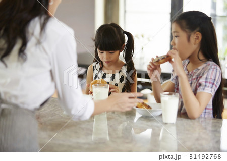 Two little girls are eating donuts and milk for breakfast. Two little girls are eating donuts and milk for breakfast. 31492768