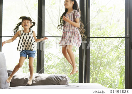 Two sisters are jumping and playing together on a sofa 31492828