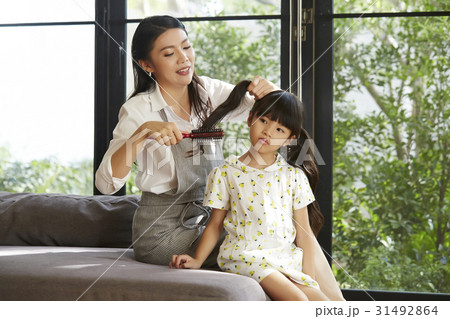 Mom is combing her daughter's hair at home 31492864