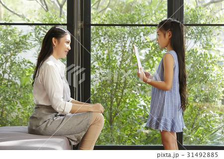 A little girl is standing and showing a book to her mother. A little girl is standing and showing a book to her mother. 31492885