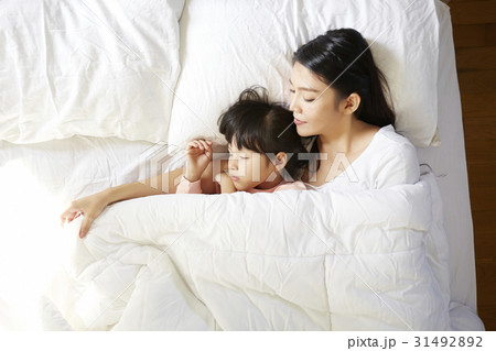 A mother and her daughter are sleeping on bed in the morning. A mother and her daughter are sleeping on bed in the morning. 31492892