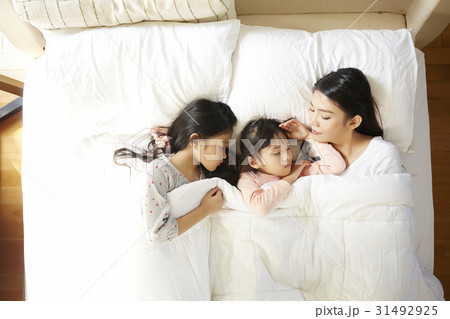 A mother with two girls are sleeping on bed at home. A mother with two girls are sleeping on bed at home. 31492925