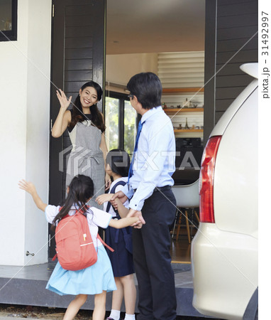 mom is waving two girls preparing to go to school with dad 31492997