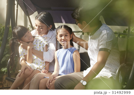 parents are talking and playing with two kids on a swing. 31492999