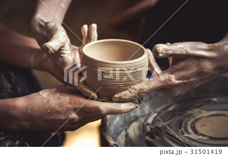 A raw clay pot in the hands of a potter A raw clay pot in the hands of a potter 31501419