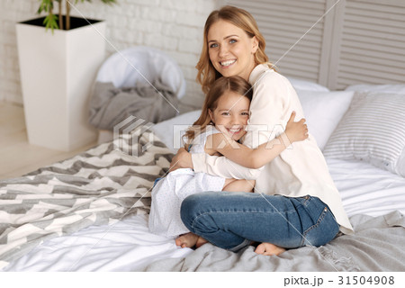 Happy mother and daughter cuddling on the bed 31504908