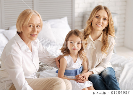 Two women sitting on bed with child in between 31504937