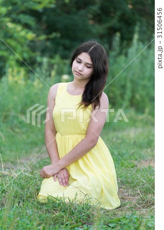The girl in yellow dress sitting on grass 31506456