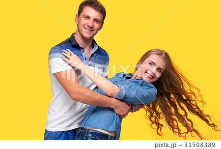 Portrait of a young couple standing against yellow Portrait of a young couple standing against yellow 31508389