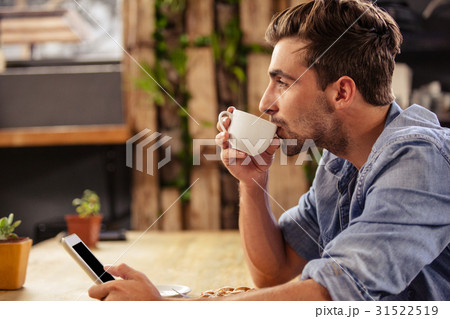 Profile view of hipster man using tablet at cafe 31522519