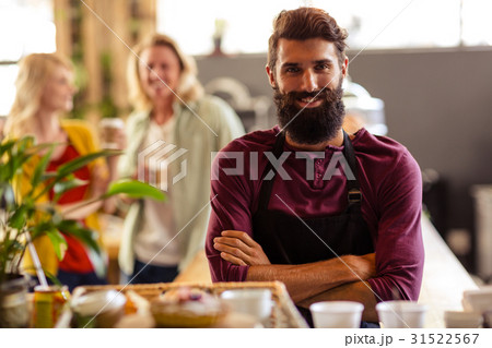 Bartender arms crossed with customers in the background Bartender arms crossed with customers in the background 31522567