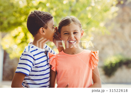Happy boy whispering a secret in girls ear Happy boy whispering a secret in girls ear 31522618