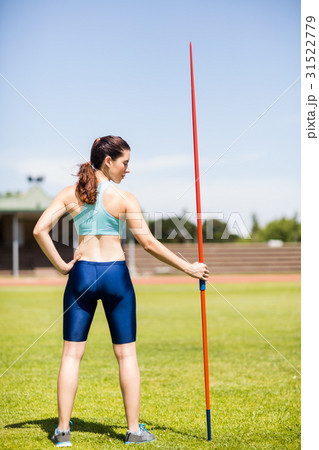 Rear view of female athlete holding a javelin in stadium Rear view of female athlete holding a javelin in stadium 31522779