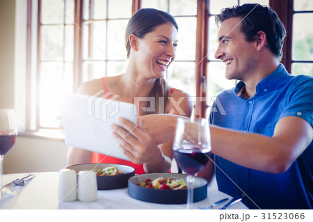 Happy couple using a digital tablet during lunch 31523066
