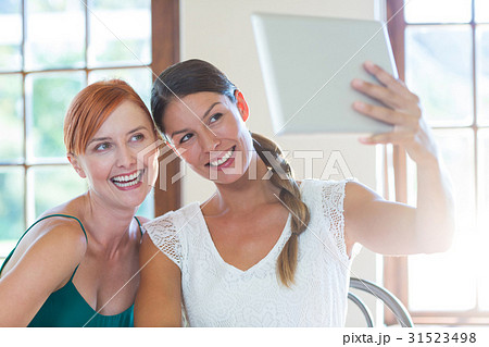 Two beautiful women taking selfie with digital tablet Two beautiful women taking selfie with digital tablet 31523498