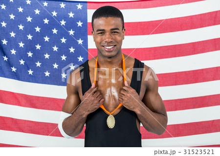 Athlete showing his gold medal in front of american flag Athlete showing his gold medal in front of american flag 31523521