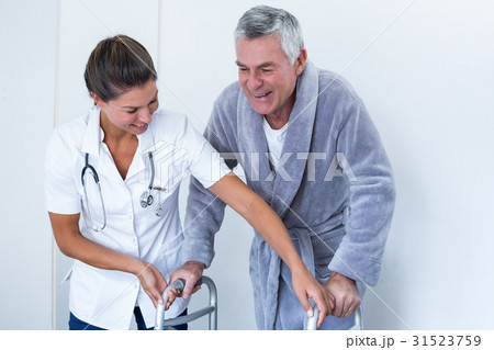 Female doctor helping senior man to walk with walker 31523759
