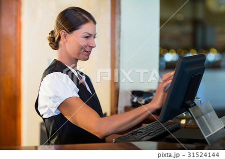 Waitress using a computer at counter 31524144