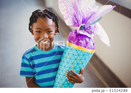 Portrait of smiling schoolboy holding gift in corridor 31524286