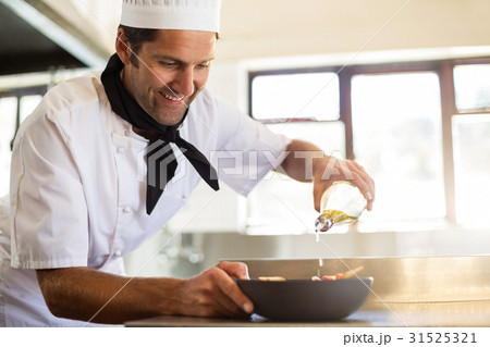 Chef pouring olive oil on meal Chef pouring olive oil on meal 31525321