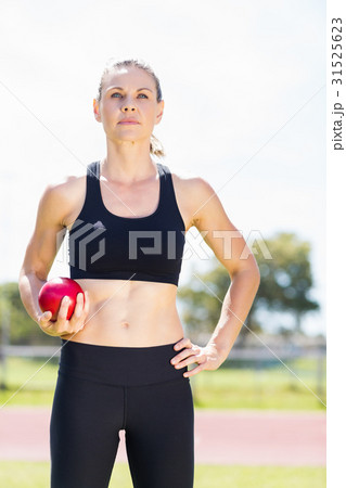 Confident female athlete holding a shot put ball 31525623