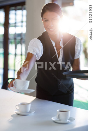 Smiling waitress serving cup of coffee Smiling waitress serving cup of coffee 31525953