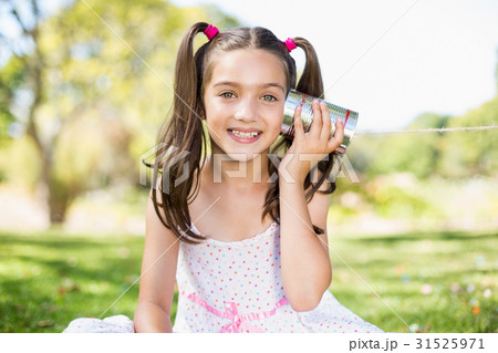 Young girl listening through tin can phone 31525971