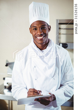 Portrait of smiling chef making notes on a clipboard Portrait of smiling chef making notes on a clipboard 31526156
