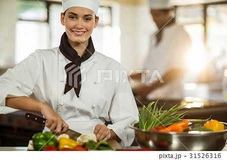 Portrait of female chef cutting vegetables Portrait of female chef cutting vegetables 31526316