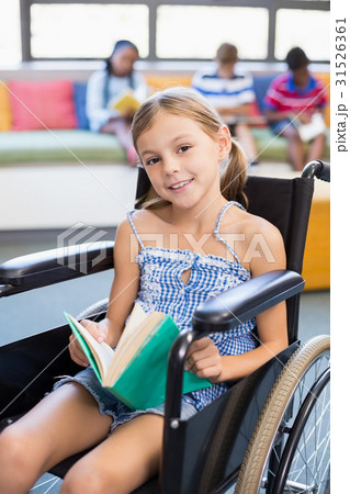 Portrait of disabled school girl reading book in library 31526361