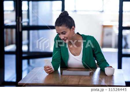 Businesswoman looking her mobile phone and holding a coffee Businesswoman looking her mobile phone and holding a coffee 31526445